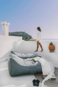 a woman walking in a white room with a couch at ARTE LINDOS SUITES in Lindos