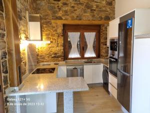 a kitchen with a granite counter top and a refrigerator at Casa Grilo in Monforte de Lemos