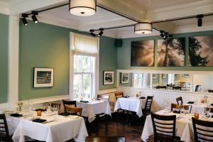 a restaurant with white tables and chairs and a window at Nicholson House at Beaujolais in Mendocino