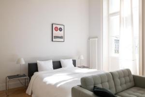 een witte slaapkamer met een bed en een bank bij 2-Bedroom Apartment with Private Library in Wenen