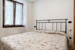 a white bedroom with a bed with a floral bedspread at Appartamento nel cuore di Tenno in Tenno