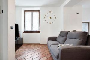 sala de estar con sofá y reloj en la pared en Appartamento nel cuore di Tenno, en Tenno