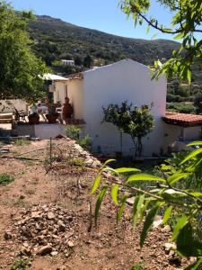 una casa bianca con una montagna sullo sfondo di ARETI Sea View Mountain Cottage ad AmigdhalokeFálion