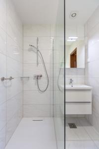 uma casa de banho branca com um chuveiro e um lavatório. em Rooms Tereza em Bled