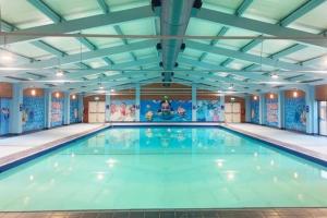 a large indoor swimming pool with blue water at 13 The Meadows New Beach Holiday Park in Kent