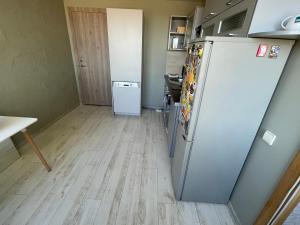 a kitchen with a refrigerator and a wooden floor at Central place with lake view in Šiauliai