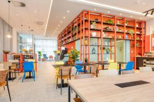 un restaurante con sillas coloridas, mesas y estanterías en B&B HOTEL Mechelen, en Malinas