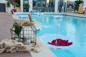 a bird cage with flowers in it next to a swimming pool at Dionisos Hotel in Malia