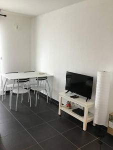 sala de estar con 2 mesas y TV de pantalla plana en Superbe T1 à bastia vue sur mer, en Bastia