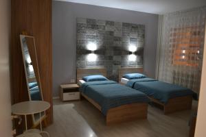 a bedroom with two beds and a table and a mirror at Lazarus Apartment in Skopje