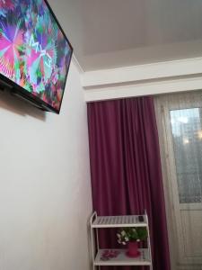 TV de pantalla plana colgada en una pared junto a una ventana en Аlmaty Arbat, en Almaty