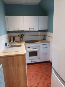 a kitchen with white cabinets and a sink at le cottage vue mer in Bénerville-sur-Mer