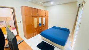 Dormitorio pequeño con cama azul y armarios de madera en Departamento Zuatynky en Asunción