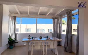 a dining room with a table and chairs in front of a window at Los Delfines Casa Nina by Rentalfue in Corralejo