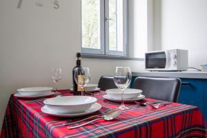 - une table avec des assiettes, des verres et une bouteille de vin dans l'établissement LUX Apartment Milano Metro M2, à Milan