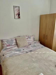 a bedroom with a bed with purple sheets and a wooden cabinet at 2 bedroom near Euston, King's Cross in London