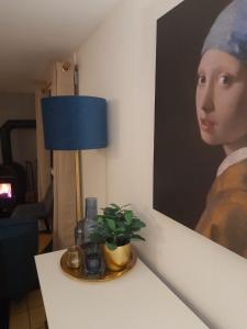 a table with a lamp and a painting of a woman at Haus Annemiek in Winterberg