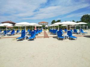 un mucchio di sedie blu e ombrelloni sulla spiaggia di Hotel Thermaikos a Korinós