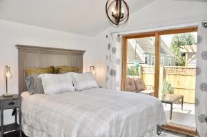 a white bedroom with a bed and a large window at Adorable Bungalow w/ Private Patio Mins away from Downtown Rapid City in Rapid City