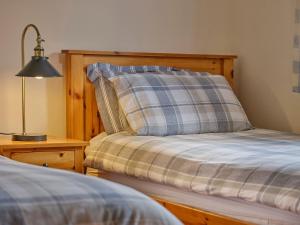 a bed with a pillow and a lamp on a table at Linhay, Pattard in Hartland