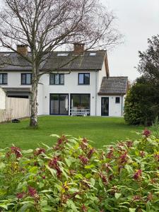 una casa blanca con un árbol en el patio en Die huis 14-Een oase van rust tussen polders en kust en Ostende