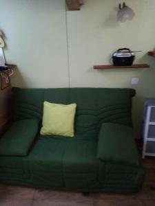 a green couch with a yellow pillow on it at La cabane in Palogneux