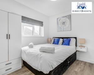 a white bedroom with a large bed with blue pillows at Modern And Stylish Two Bedroom Apartments by Direct2hosts With Great Location! in London