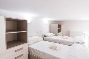 - 2 lits dans une petite chambre aux murs blancs dans l'établissement Loft via morosini centro Varese - IXIHOME, à Varèse
