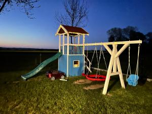 a playground with a slide and a car in the grass at Black Horse in Pasłęk