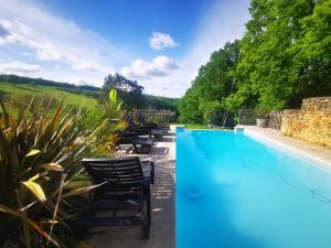 a pool with chairs next to a stone wall at Gîte Les Combes Montignac Lascaux in Montignac