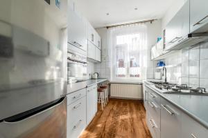 a white kitchen with wooden floors and white cabinets at Rooms in City Center in Gdańsk