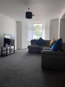 a living room with a couch and a tv at Lovely stylish apartment with breathtaking views. in Llanddulas