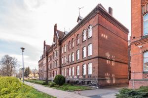 a large red brick building on a city street at Rooms in City Center in Gdańsk