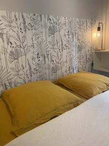 sypialnia z łóżkiem z żółtą poduszką i tapetą w obiekcie Oxalis w mieście Bagnères-de-Bigorre