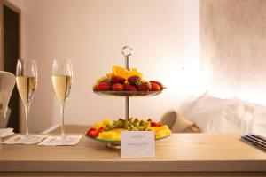 a tray of fruit on a table with two glasses of wine at Meravigghia Suites Cefalù in Cefalù