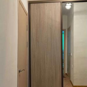 a wooden closet with a mirror in a room at Уютная квартира in Taraz