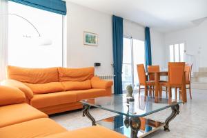een woonkamer met oranje meubels en een tafel bij VILLA ADELAIDA in L'Eucaliptus