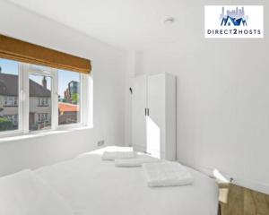 un letto bianco con cuscini bianchi e una finestra di Three Bedroom Beautiful & Comfy Acton Gem Apartment by Direct2hosts With King Beds & Free Parking! a Londra