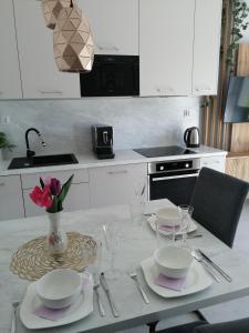 a white kitchen with a table with a vase of flowers at Apartament Zielone Wzgórze 2 in Jelenia Góra
