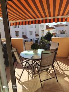 una mesa y sillas en un balcón con sombrilla en APARTAMENTO CASARES PLAYA, en San Luis de Sabinillas