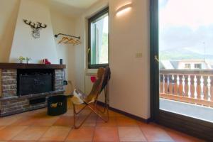 ein Wohnzimmer mit Kamin und einem Stuhl neben einem Fenster in der Unterkunft Casa Camino - 200m dagli impianti del Baradello in Corteno Golgi + 15 Fotos