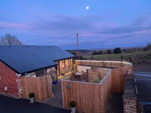 a house with a wooden fence next to a building at Penburren at Minster Farm West in Hereford