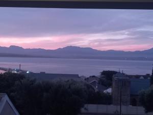 - une vue sur l'eau et les montagnes au coucher du soleil dans l'établissement Barmarine Luxury Holiday Home, à Mossel Bay