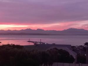 a sunset over a body of water with mountains at Barmarine Luxury Holiday Home in Mossel Bay