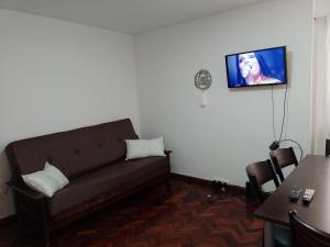 sala de estar con sofá y TV en la pared en Departamento en el Centro Histórico de Rosario en Rosario