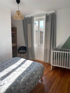 a bedroom with a bed and a crib and a window at Gite de Tom et Mag classé 3 * Clevacances in Pontgibaud