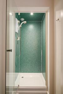 a shower with a glass door in a bathroom at Vibrant Leith Flat in Edinburgh