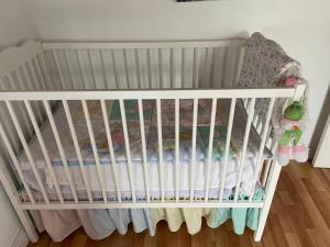 a white crib in a room with a wooden floor at Maria's Haven in Santo António