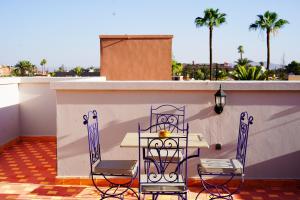 a table and chairs on a balcony with palm trees at VILLA YOUSRA in Marrakech