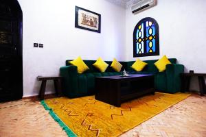 - un salon avec un canapé vert et des oreillers jaunes dans l'établissement VILLA YOUSRA, à Marrakech